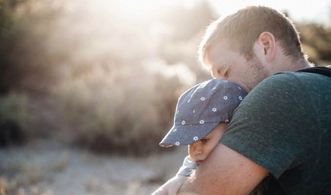 Pappa som kramar barn i solljus