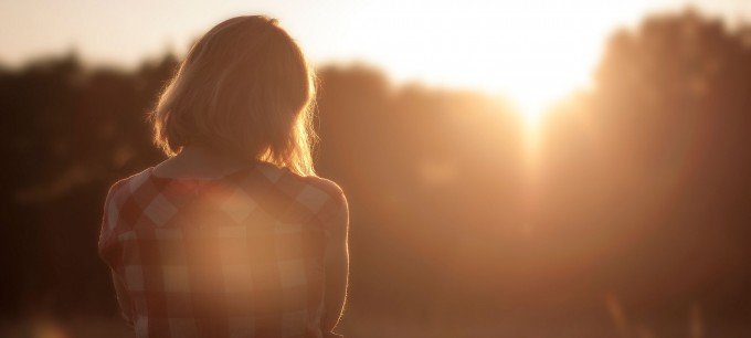 En kvinna står ensam och tittar på solnedgång.