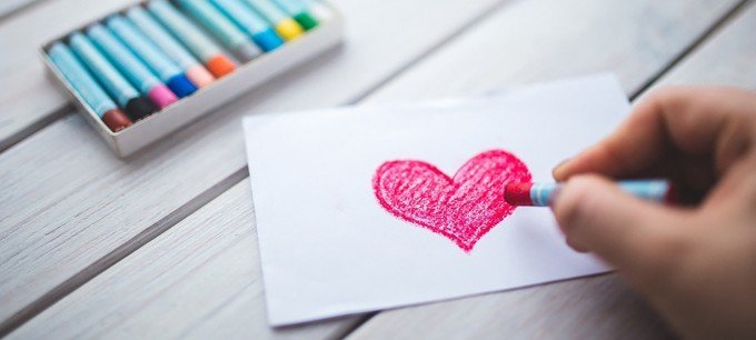 Person som ritar ett hjärta med en krita.