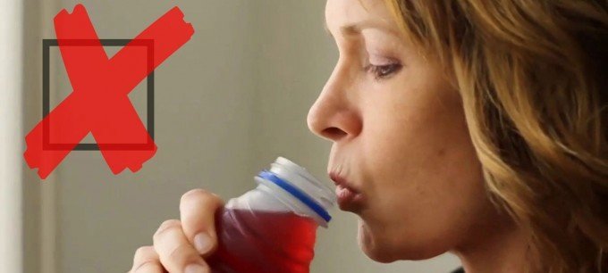 En kvinna dricker en flaska tranbärsjuice.