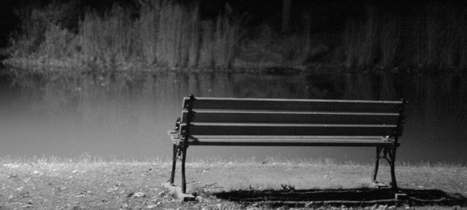 En tom bänk i ett dystert, svartvitt landskap.