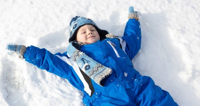 Pojke som ligger i snön och gör snöänglar. Tydligen sker influensautbrott alltid vid köldknäpp enligt forskare.
