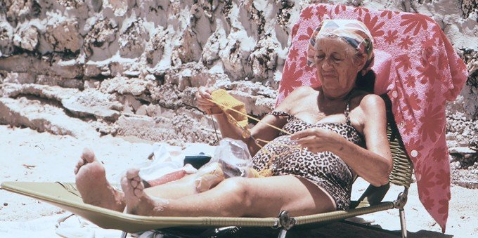 Äldre kvinna som ligger i en solstol och stickar.