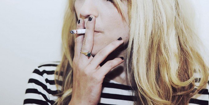 Ung kvinna som röker en cigarett.