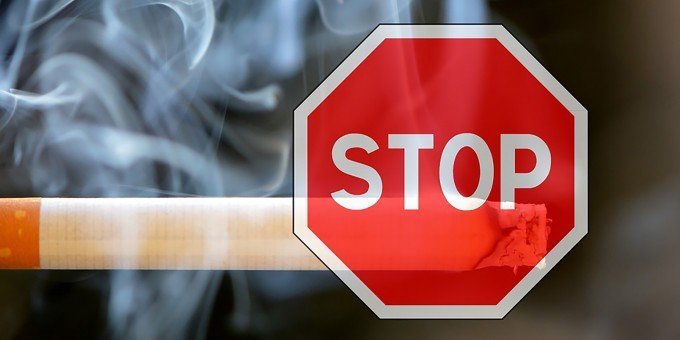 En tänd cigarett med en stopp-skylt framför.