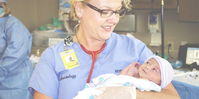 Barnmorska som håller i en nyfödd bebis.