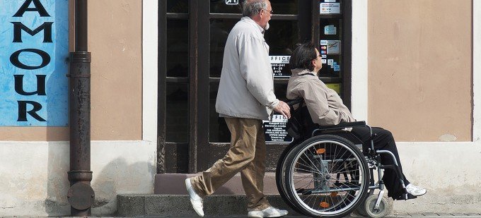 Äldre man som skjuter en ALS-patient med rullstol.