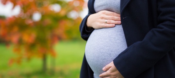 Gravid kvinna med covid-19 tar sog på magen.